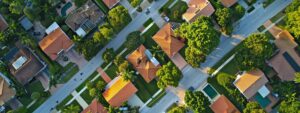 a dramatic aerial view of a residential neighborhood in pompano beach showcasing multiple roofs with visible signs of wear and crisis, illuminated by the late afternoon sun highlighting the urgency of roofing services.